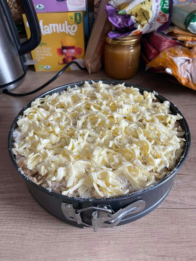 Obuolių pyragas su manais kepimo formoje, tarkuotas sviestas ant viršaus