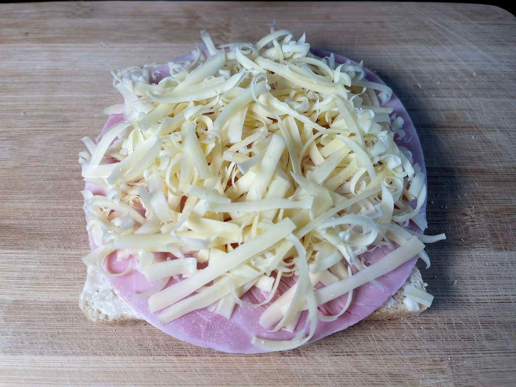 Croque-monsieur karštas sumuštinis, duona, padažas, kumpis ir tarkuotas sūris