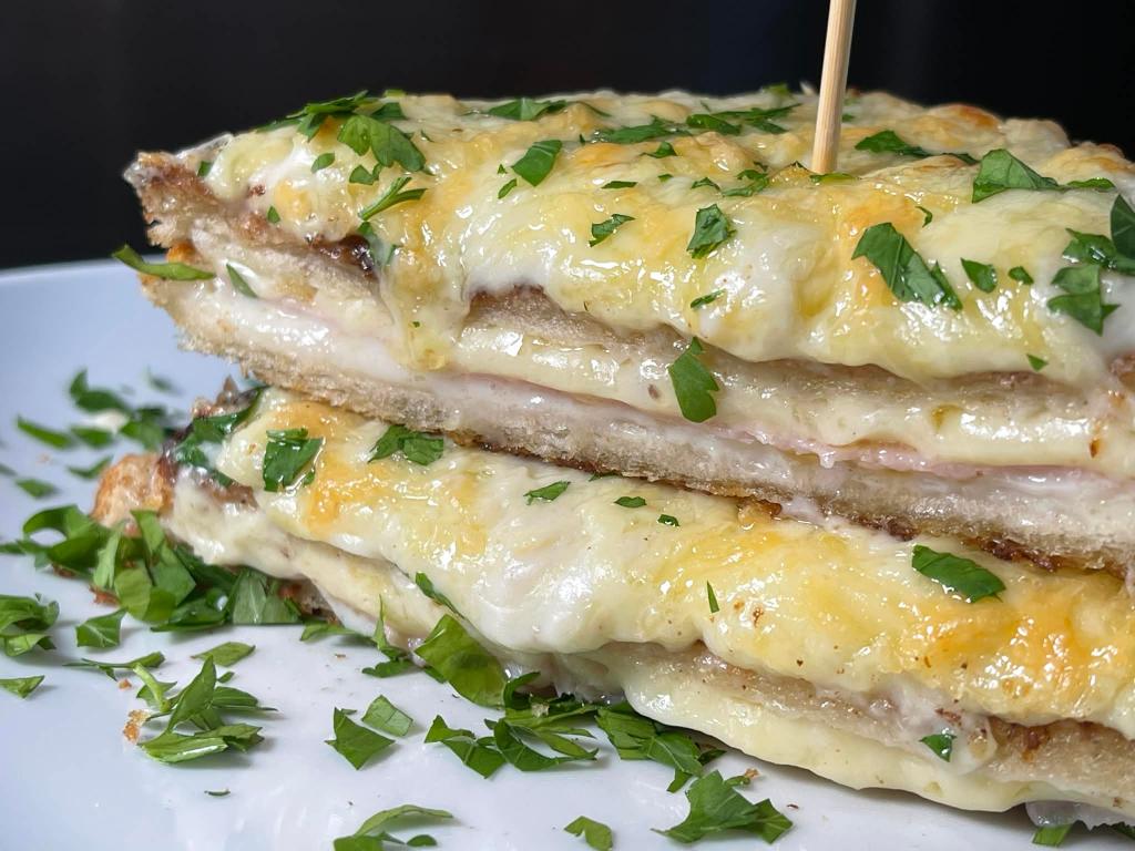Perpjautas Croque-monsieur karštas sumuštinis lėkštėje