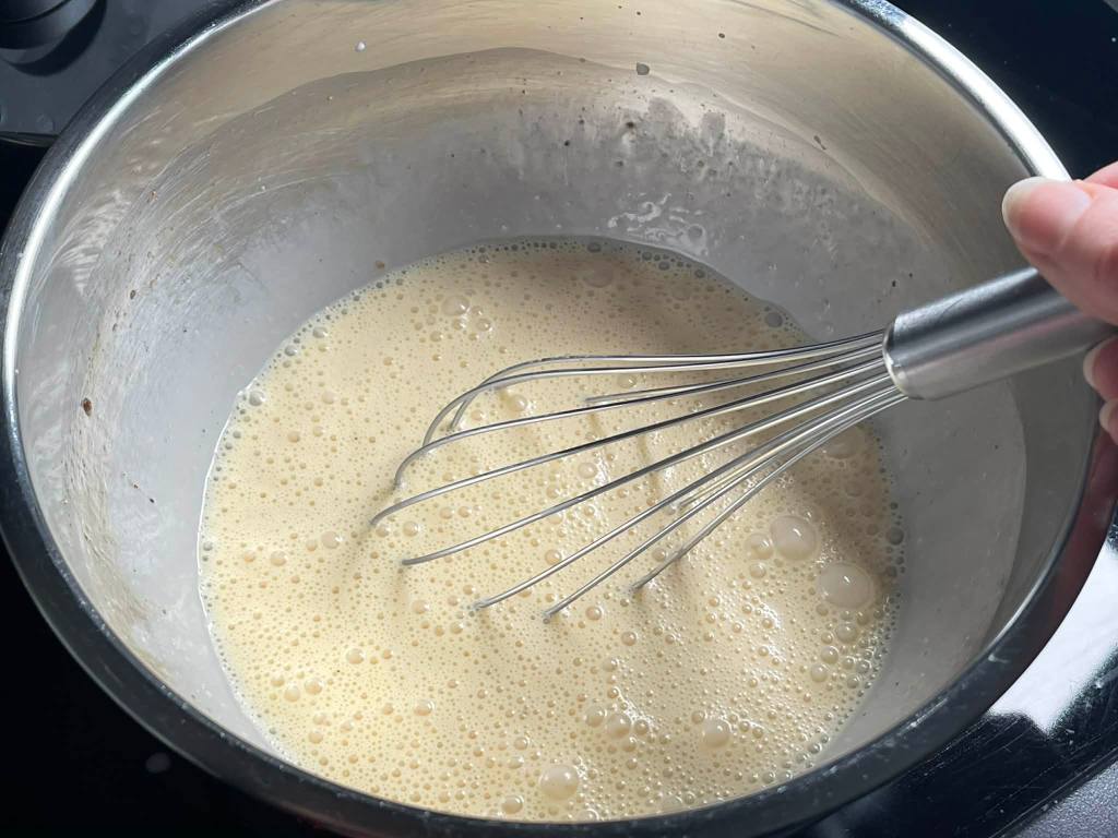 Kiaušinių ir grietinėlės plakinys dubenyje kišui su porais