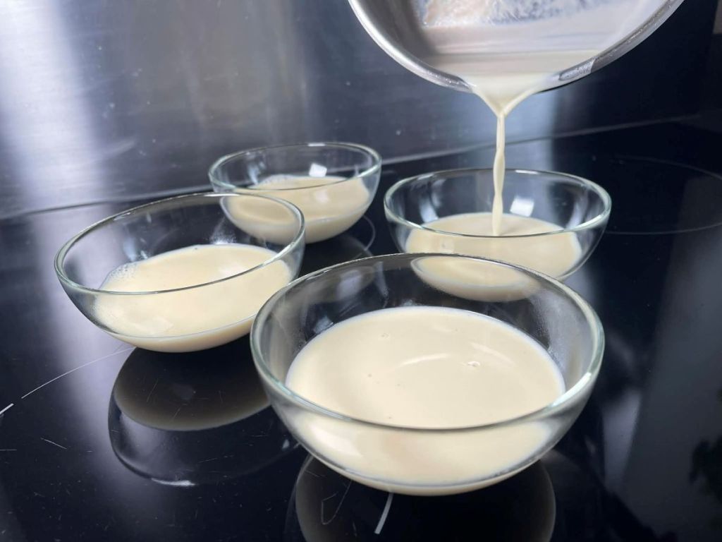 Paruošta panna cotta masė pilama į indelius.
