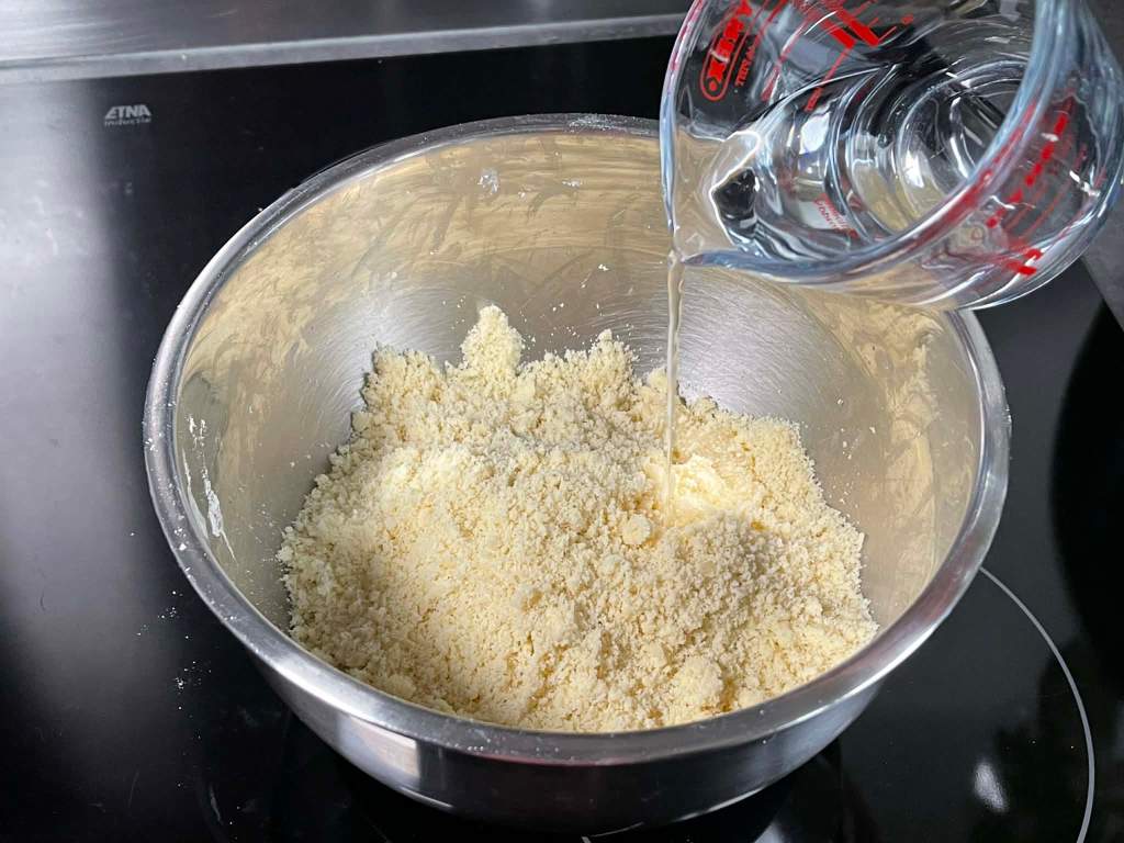 Trapi tešla, į susiformavusius trupinius įpilamas vanduo