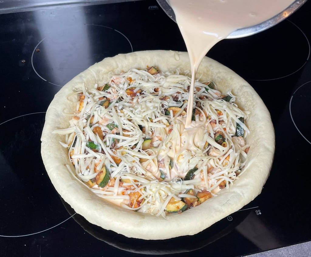 Ant kišo pagrindo sudėtų ingredientų pilamas kiaušinių ir grietinėlės plakinys