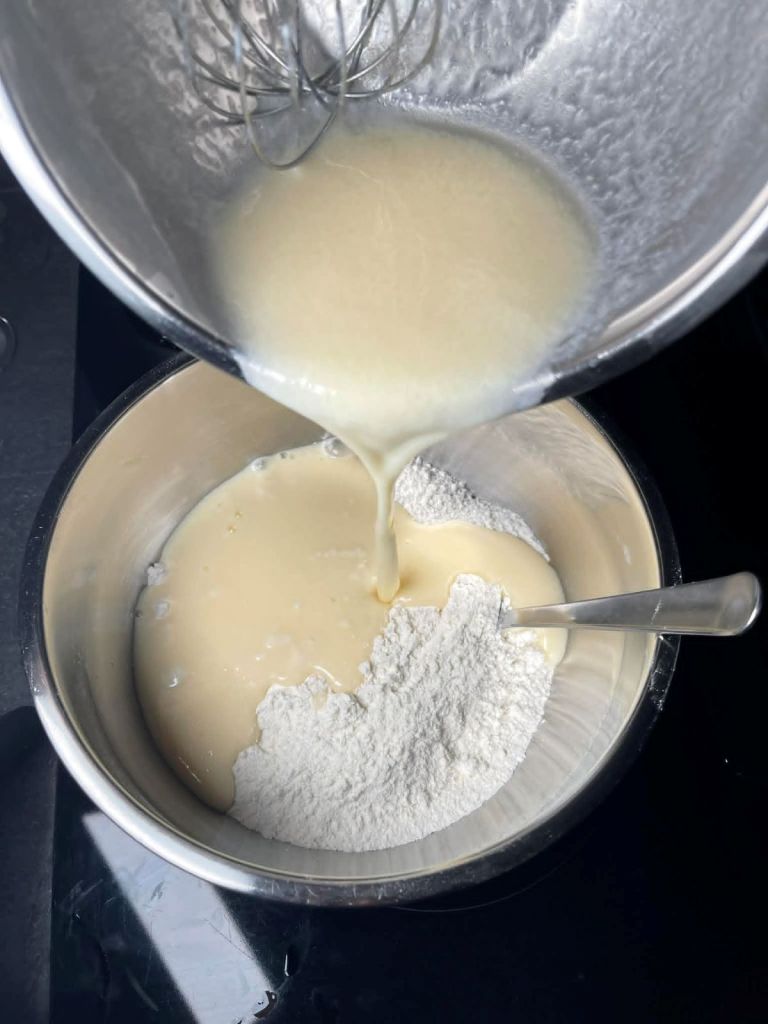Išplakti skysti ingredientai pilami į išmaišytus sausus ingredientus dubenyje.