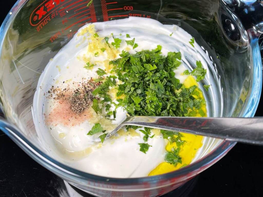Jogurtinis česnakinis padažas su citrina žolelėmis,  jogurtas ir kiti ingredientai dubenyje