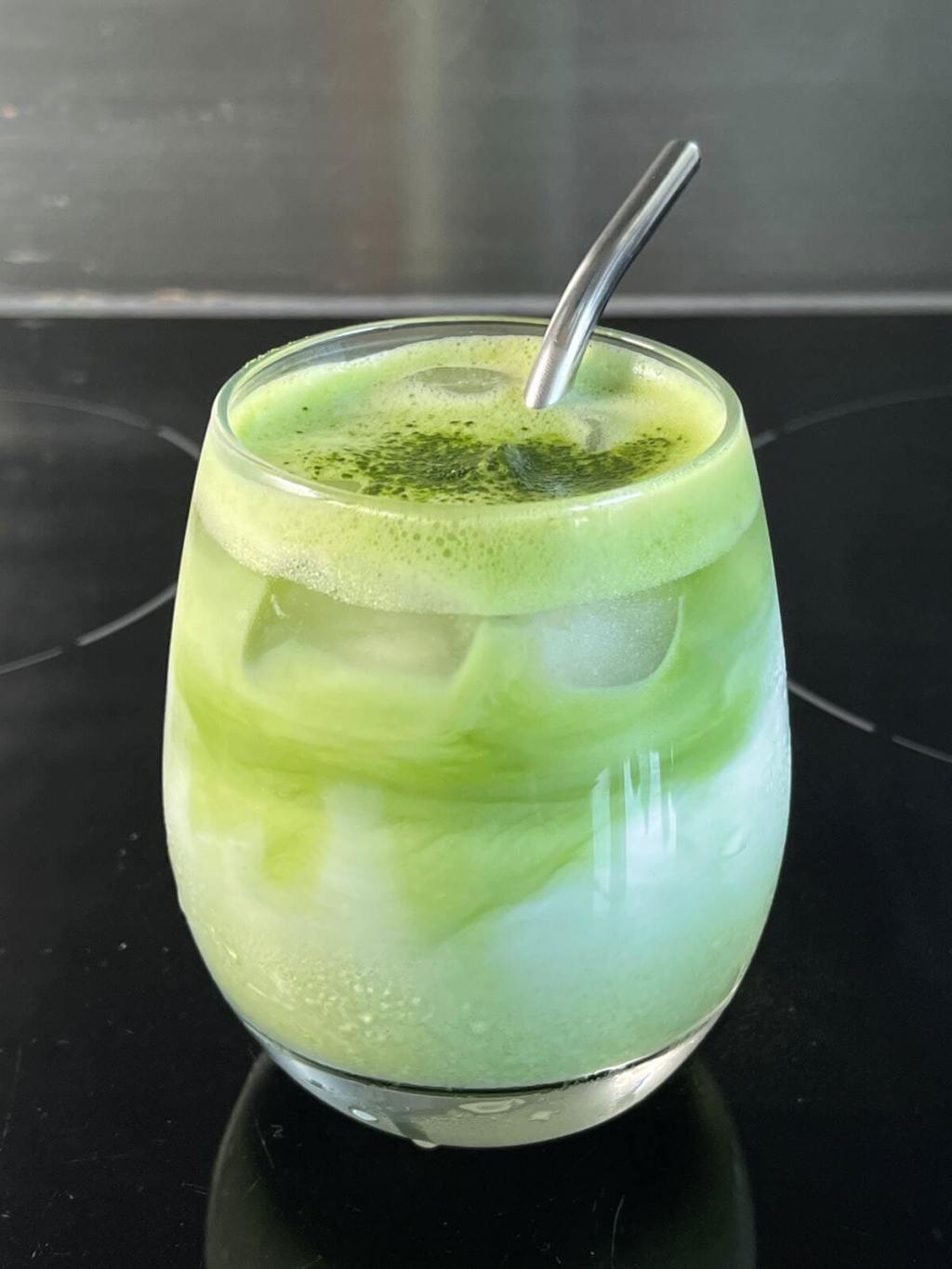 Ledinė matcha latte stiklinėje su šiaudeliu