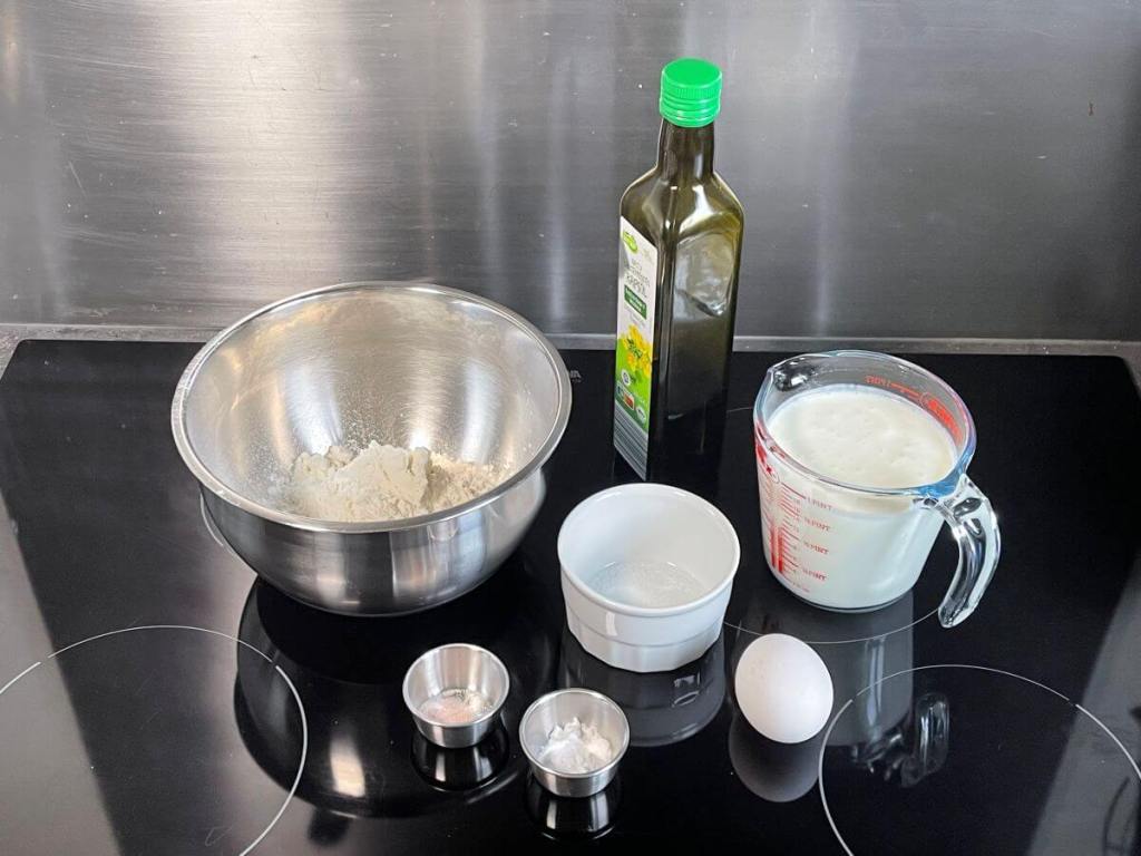 Kefyrinių blynų ingredientai: miltai, soda, kefyras, kiaušinis, cukrus, druska ir aliejus.